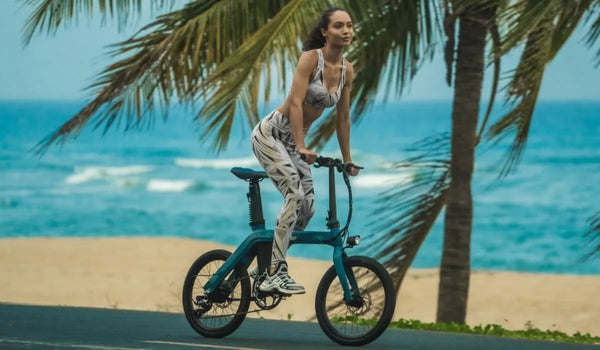 A fit woman is riding a fiido D11 electric bike on the beach