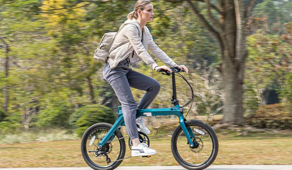 A woman rides a Fiido X electric bike through a lush park