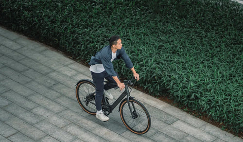 A man riding a Fiido C21 lightweight city electric bike on city streets.