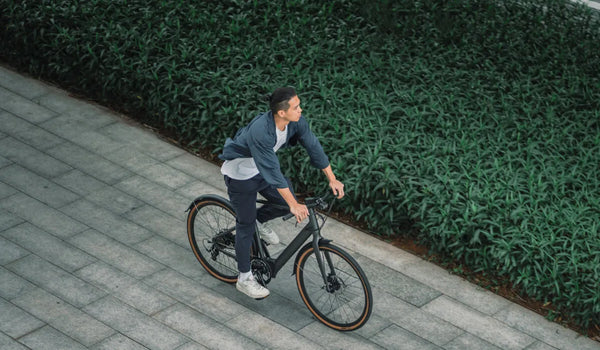 A man riding a Fiido C21 lightweight city electric bike on city streets.