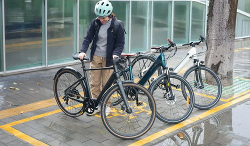 A woman is parking the Fiido C21 lightweight electric bicycle by the roadside.