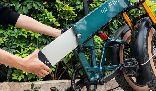 A man is removing the external battery of a Fiido M1 PRO electric bicycle.