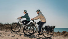 A couple is riding their Fiido Nomads Pro e-bikes along a mountain road.
