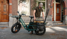 A man rides a Fiido T2 cargo e-bike to go fishing outdoors.