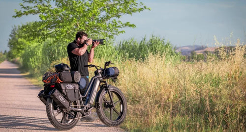 A man takes a Fiido Titan long-range e-bike with a three-battery setup for photography.