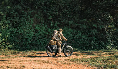 The man is riding a Fiido Titan electric bicycle, preparing for a hunting trip.