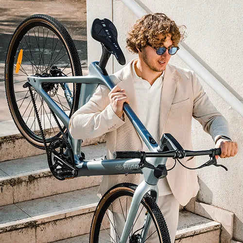 Man carrying a Fiido carbon fiber e-bike downstairs